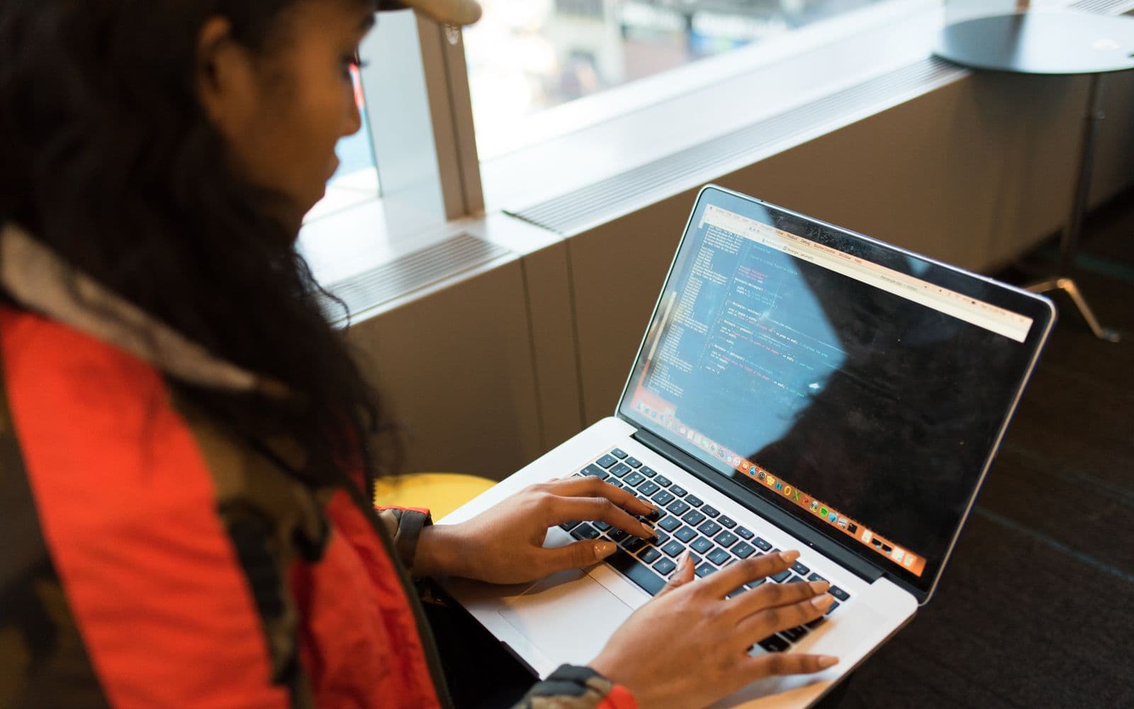 A builder at a laptop with their hands on the work, code open in front of them